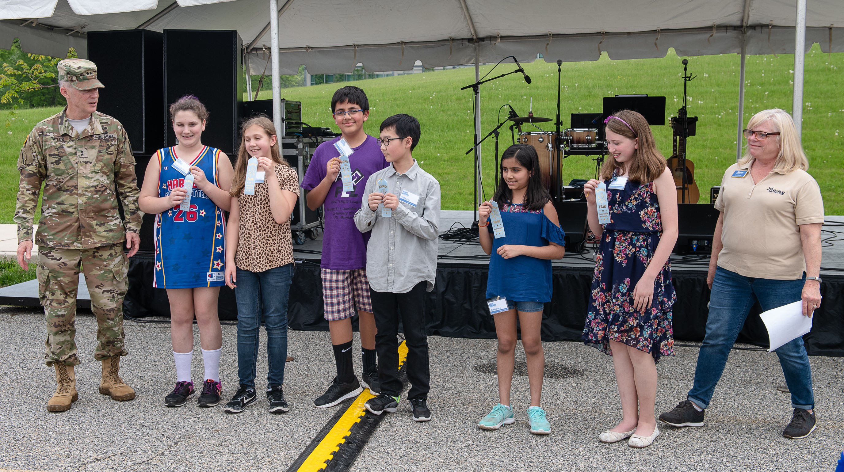 Student Awardees stand on stage with ribbons
